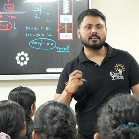 Deepak Sir explaining a physics problem on the digital board